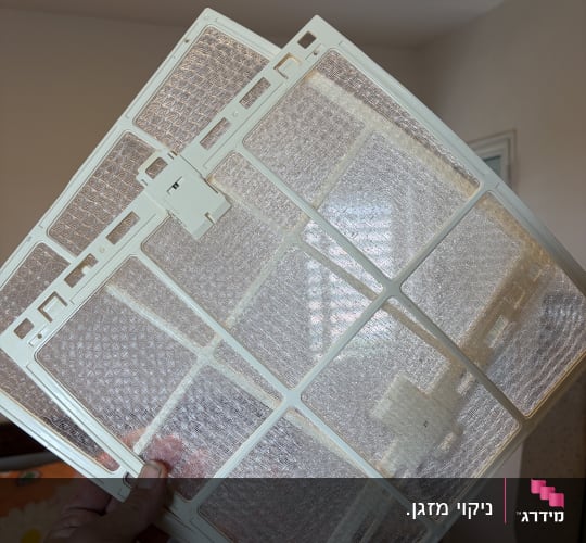 פילטר מזגן מוחזק ביד בחדר מואר